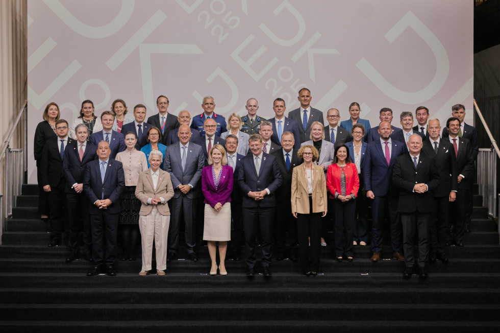 Uradna skupinska fotografija, kjer udeleženci stojijo v štirih vrstah na temnem stopničastem podestu, v ozadju je bledo rdeč pano z belim tiskom znaka danskega predsedovanja Svetu Evropske unije EU2025DK.
