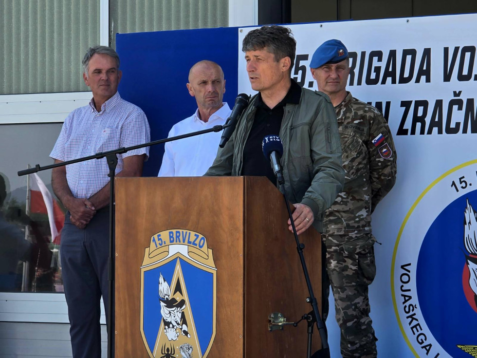 Minister med govorom stoji za govornico z znakom 15. brigade. Za njim so drugi visoki gostje