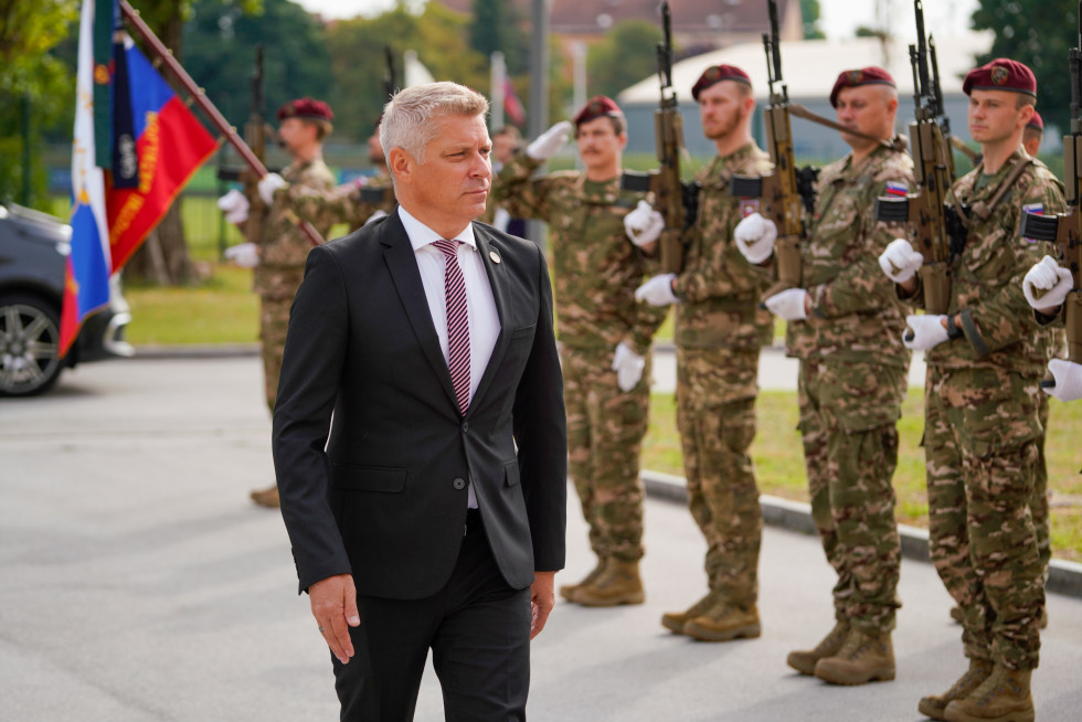 Minister Hajdinjak hodi pred vojašnico mimo vojakov v častnem postroju in prapora zastave Slovenske vojske.
