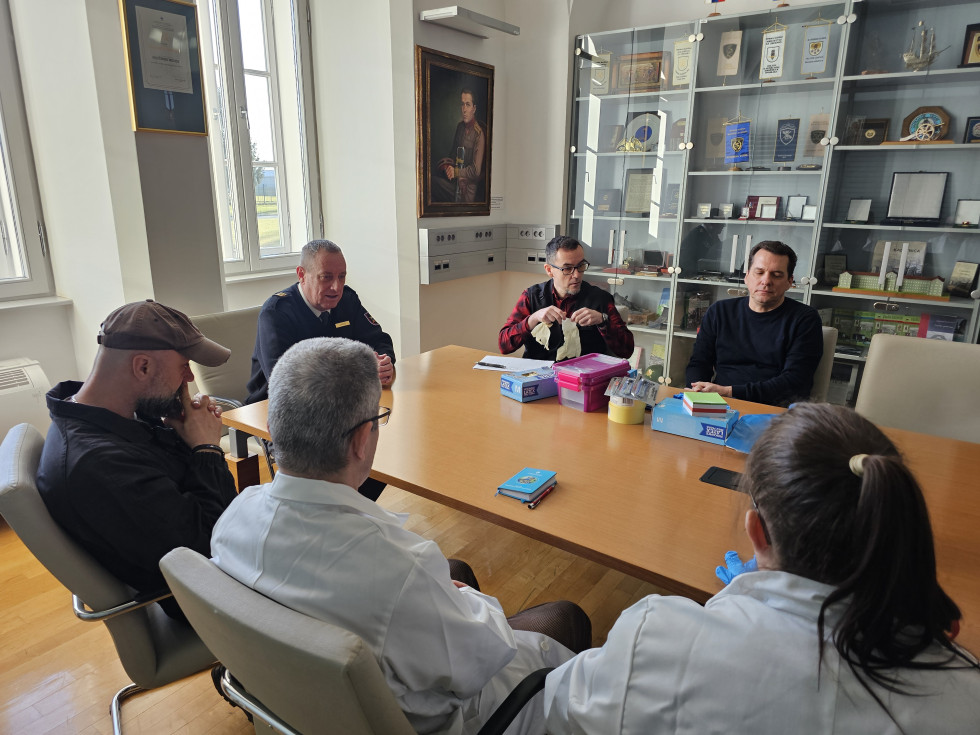 Udeleženci vaje sedijo za mizo pred začetkom vaje