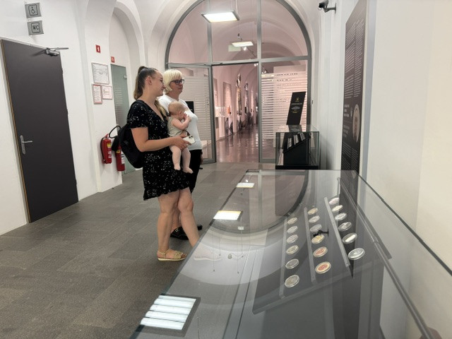 Obiskovalci si ogledujejo vitrine z razstavnimi eksponati