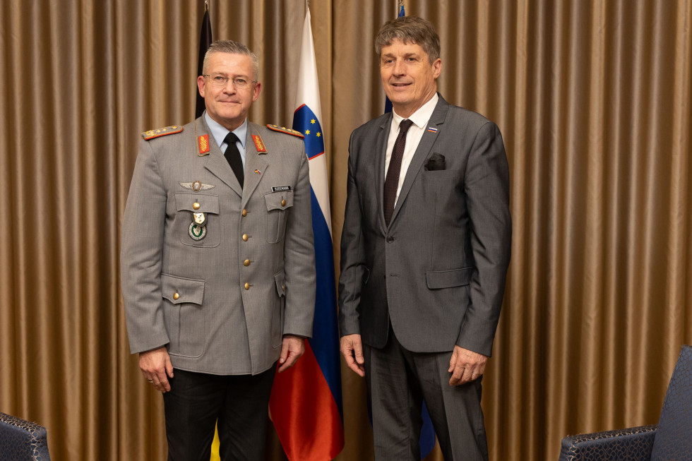 Minister in general stojita pred zastavami Nemčije, Slovenije in EU