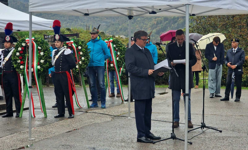 Sekretar med govorom stoji pred mikrofonom na ploščadi pred spomenikom