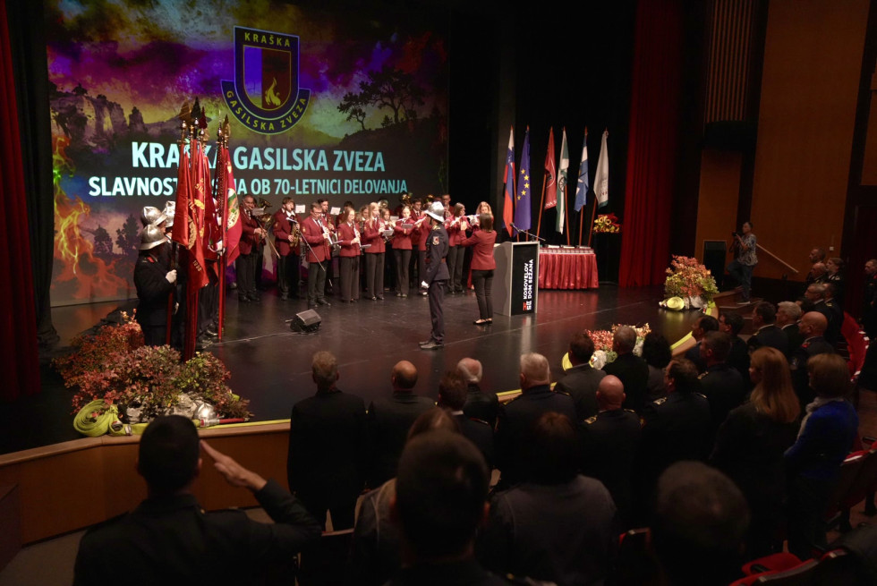 Oder z nastopajočimi in napisom ob visokem jubileju ter udeleženci proslave, ki stojijo pred odrom