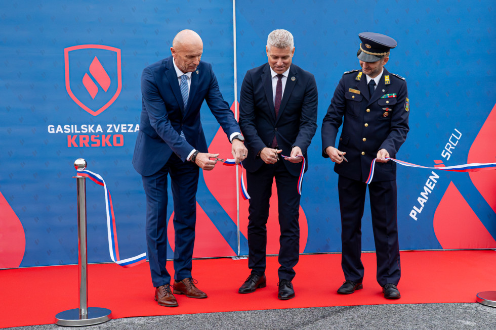 Minister, predstavnik občine Krško in gasilske zveze režejo trak pred novimi prostori zveze