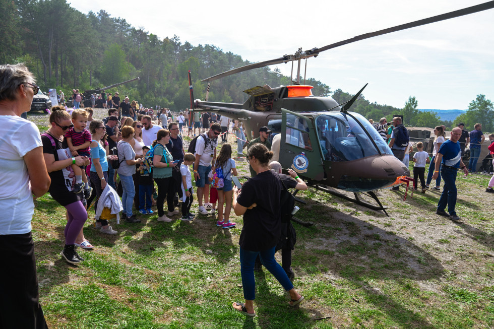 Na travniku osrednjega prizorišča si obiskovalci si ogledujejo helikopter Slovenske vojske.