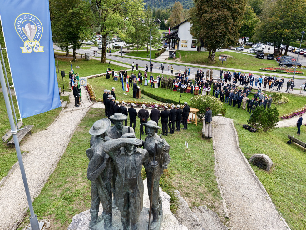 Z letalnikom posneto prizorišče slovesnosti. V ospredju je spomenik prvopristopnikom na Triglav in zastava slovenskih gornikov