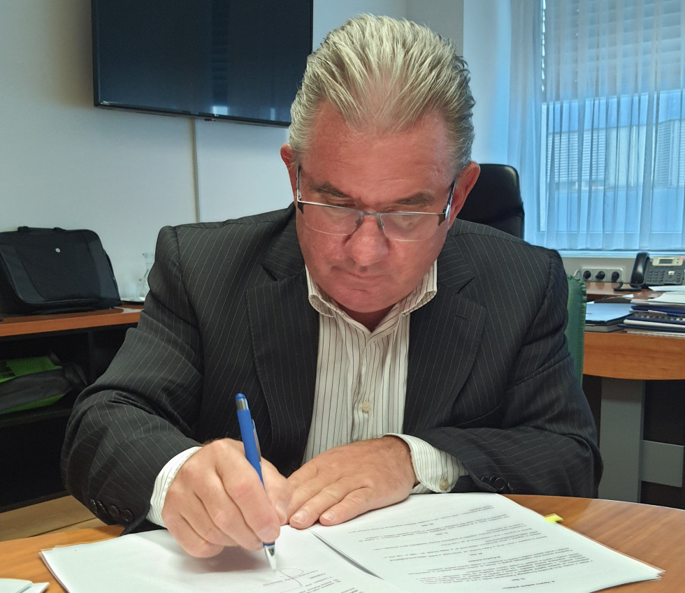 Minister podpisuje dokument za delovno mizo