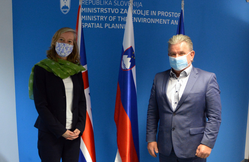 Minister in veleposlanica stojita pred slovensko in evropsko zastavo