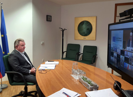 Minister sits at the table in front of the screen which monitors session