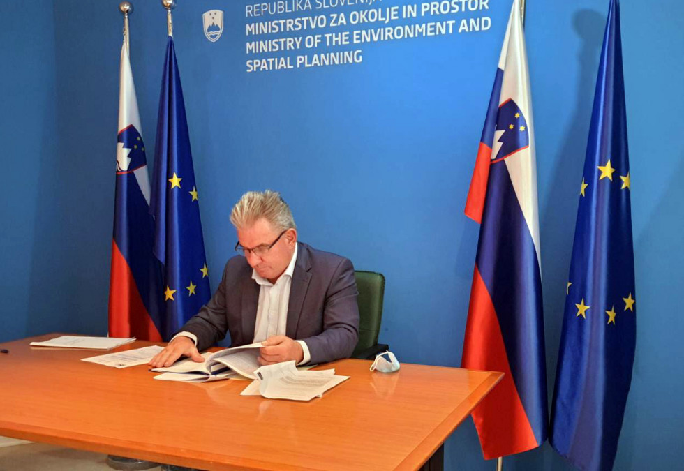 Minister Vizjak behind the table in front of the flags