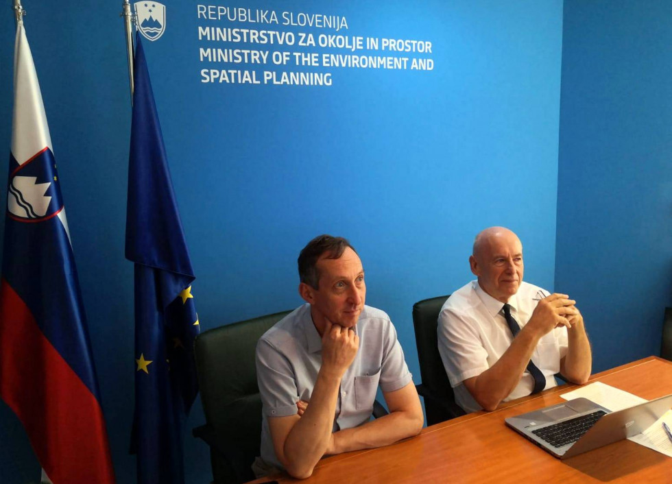 Sogovornika sedita za mizo pred televizijo. Zadaj napis MOP in slovenska ter evropska zastava
