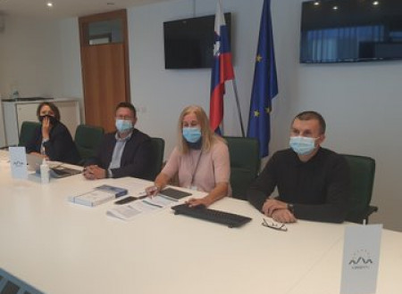 Predstavniki ministrstva sedijo za mizo v sejni sobi, zadaj zastave Slovenije in EU