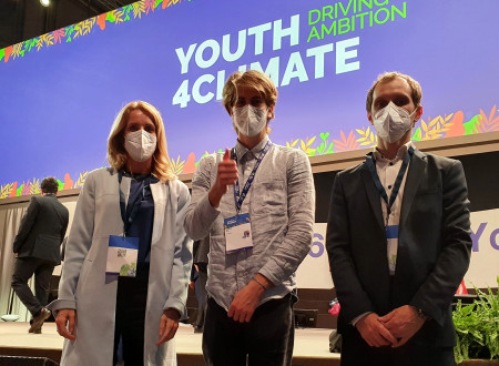 Vodja Službe za EU zadeve na MOP Katja Piškur, mladi delegat iz Slovenije in Luka Vombek iz MOP stojijo v dvorani. V ozadju napis Youth for climate.