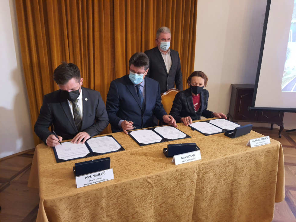 Državni sekretar Aleš Mihelič, župan Ivan Molan in državna sekretarka dr. Metka Gorišek med podpisom, minister mag, Vizjak stoji v ozadnju.