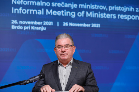 Minister na govorniškem pultu pred ozadjem dogodka
