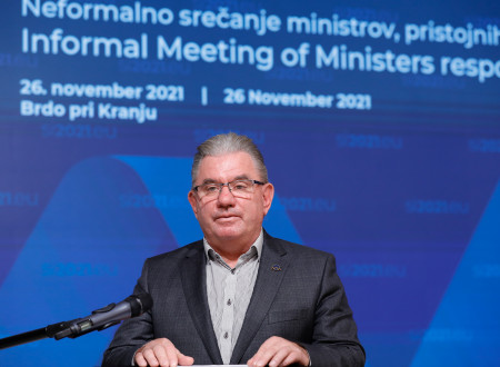 Minister na govorniškem pultu pred ozadjem dogodka