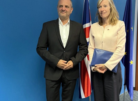 Minister in veleposlanica stojita pred zastavami Slovenije, EU in Združenega kraljestva
