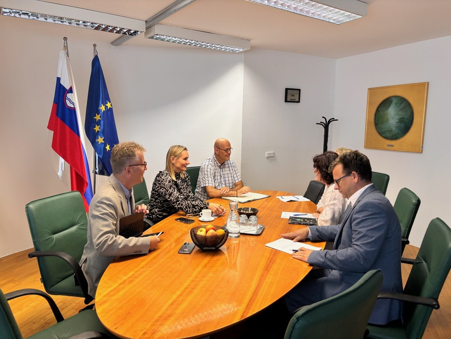 udeležneci srečanja sedijo za mizo in se pogovarjajo