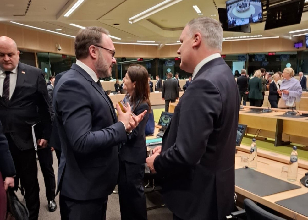 Minister in komisar stojita in se pogovarjata. V ozadju dvorana plenarnega zasedanja evropskih energetskih ministrov.