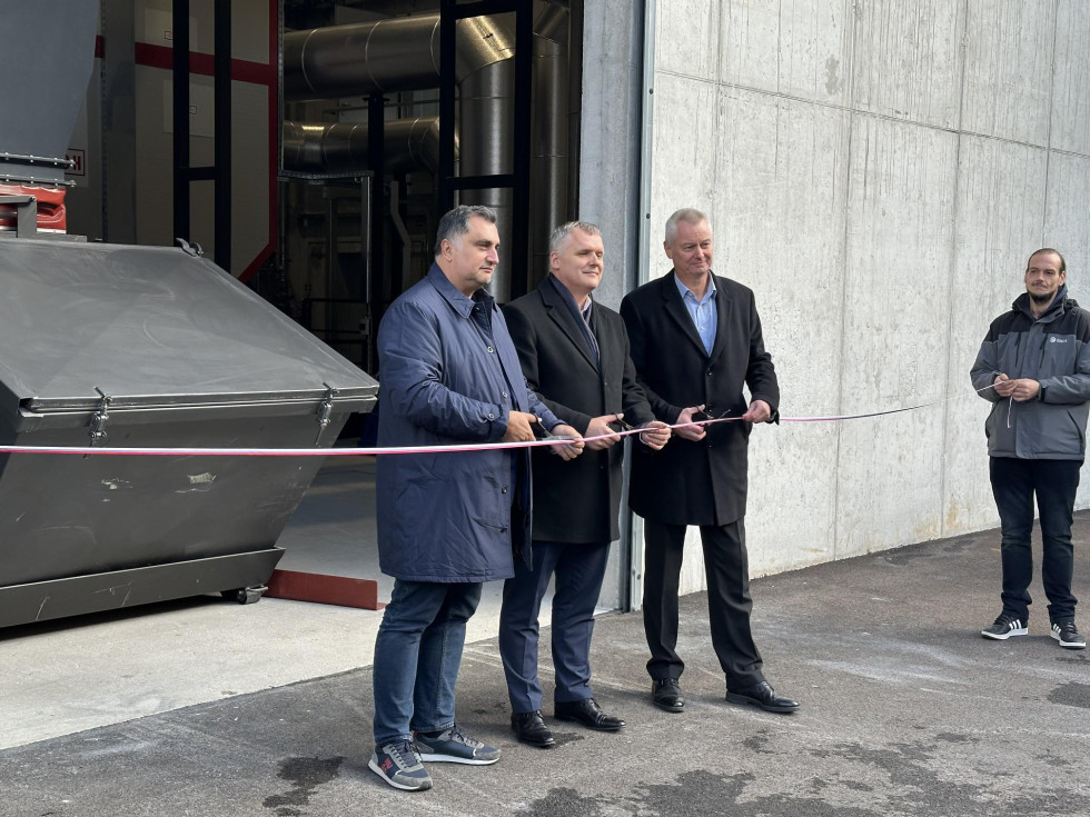 trije moški stojijo ob otvoritvenem traku