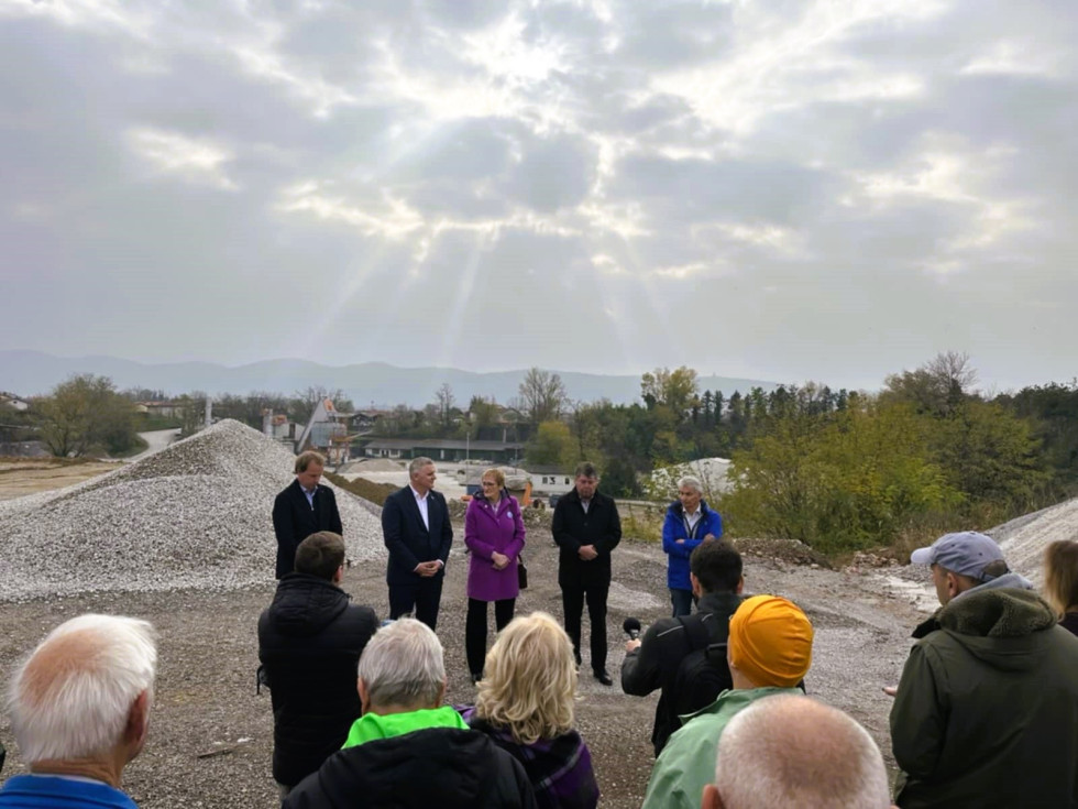 Govorci pred kupom kamenja, pred njimi novinarji