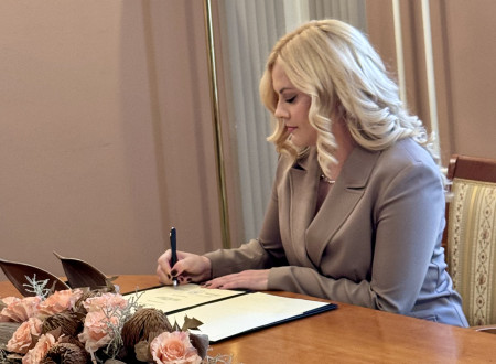 Lea Hudobivnik, okrajna državna tožilka na Okrožnem državnem tožilstvu v Ljubljani, sede podpisuje potrdilo o prisegi v sejni sobi Ministrstva za pravosodje.