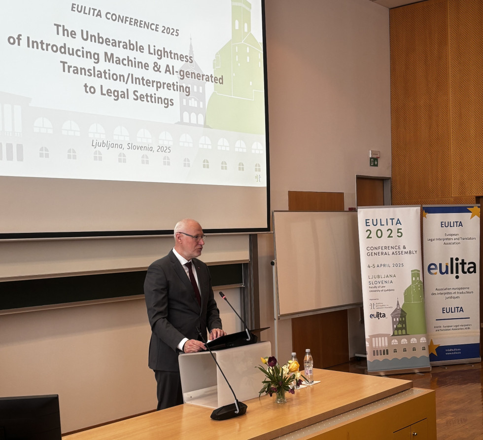 Dr, Milan Brglez za govornico na Pravni fakulteti nagovarja mednarodno konferenco Evropskega združenja pravnih tolmačev in prevajalcev. V ozadju napis z naslovom konference.