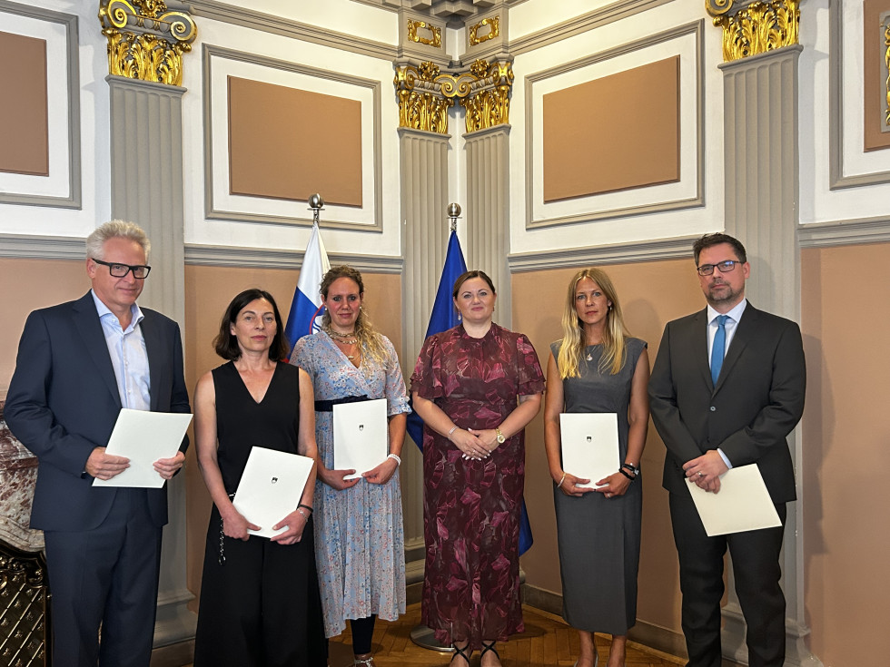 Skupinska fotografija petih oseb z listinami v reprezentančnem prostoru.