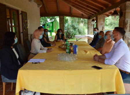 Vodstvo ministrstva in izvajalske organizacije Center Sonček Elerji sedijo za mizo in se pogovarjajo