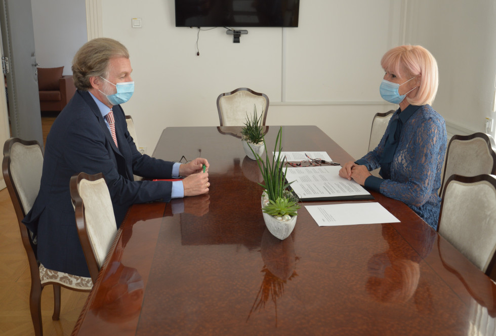 Ministrica Lilijana Kozlovič in španski veleposlanik v Sloveniji Juan Arísteguije Labord sedita za mizo in se pogovarjata
