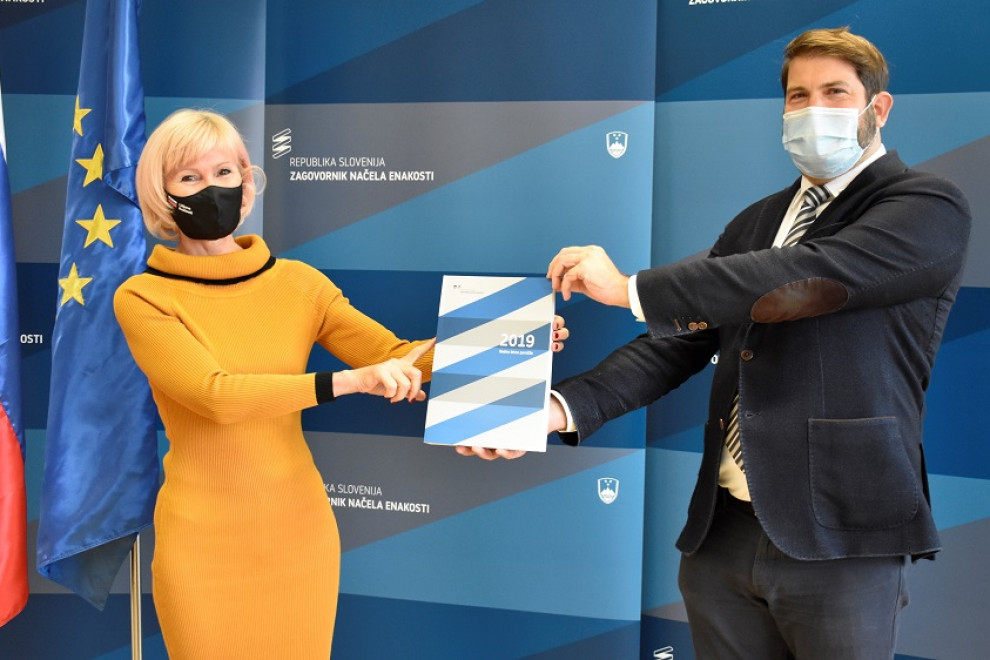 Ministrica za pravosodje Lilijana Kozlovič in zagovornik načela enakosti stojita in v roki držita letno poročilo zagovornika v letu 2019