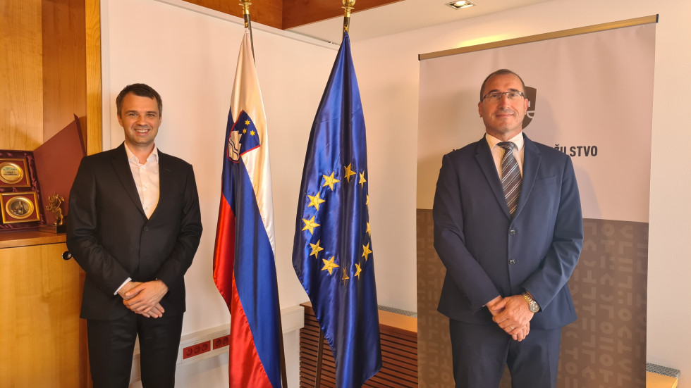 Na fotografiji pred slovensko in evropsko zastavo stojita minister Dikaučič in GDT Šketa