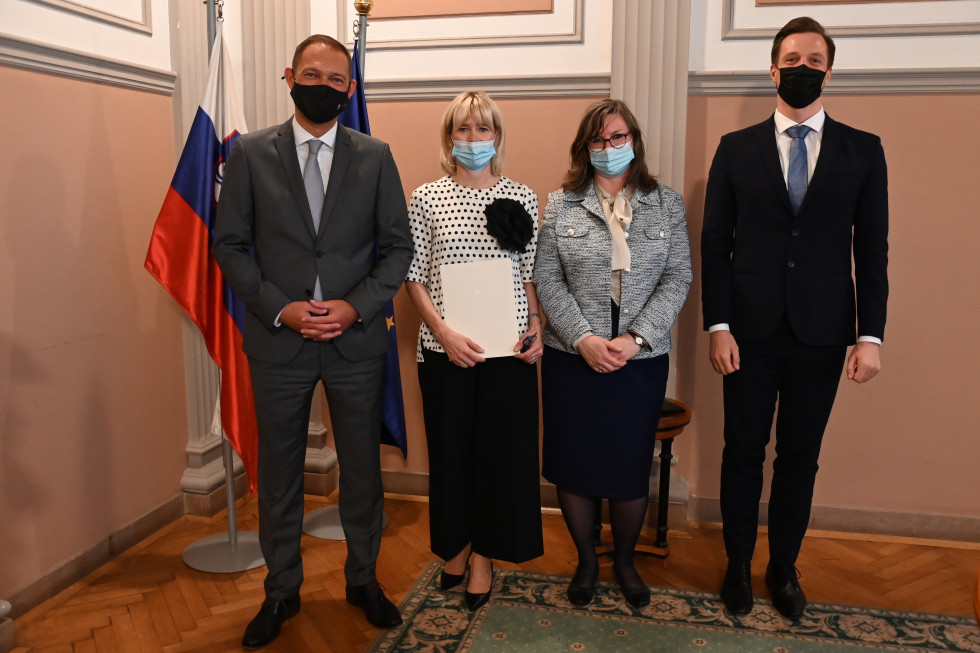 Na fotografiji, pred slovensko in evropsko zastavo, stojijo, z desne proti levi, državni sekretar na ministrstvu, namestnica generalnega državnega odvetnika, višja državna odvetnica ter generalni državni odvetnik