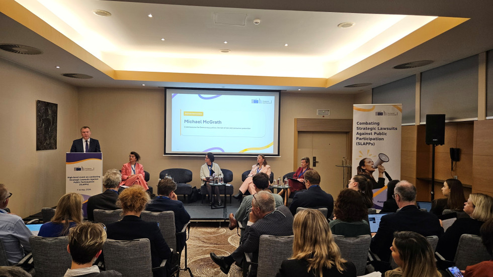 Na odru govornik nagovarja udeležence, ob njem pa poteka panelna razprava strokovnjakov.