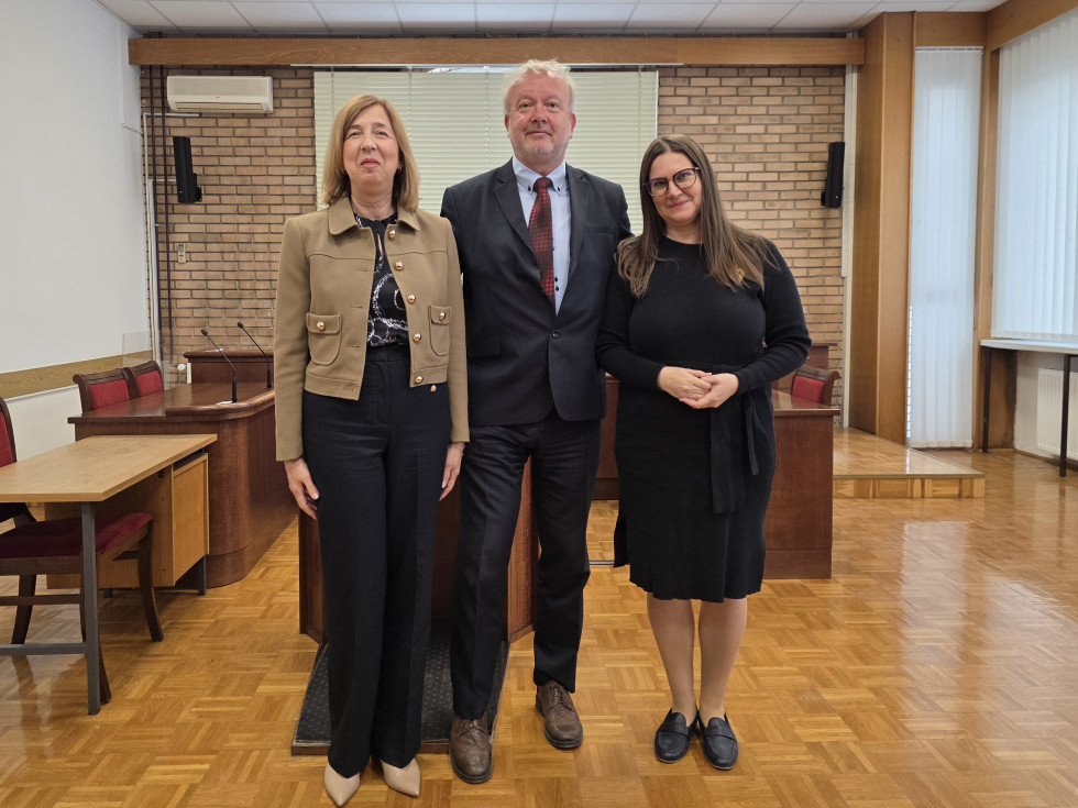 Ministrica za pravosodje z dvema sogovornikoma stoji v sodni dvorani pred sodniškim pultom.