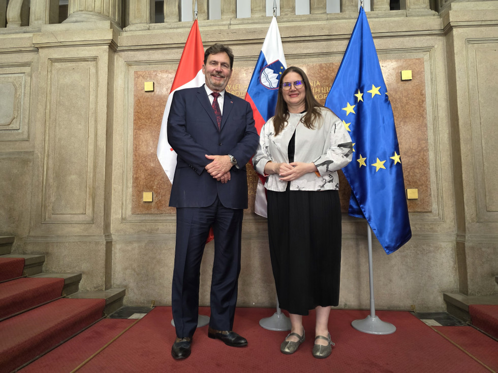 Ministrica in predsednik Vrhovnega sodišča pozirata pred zastavami