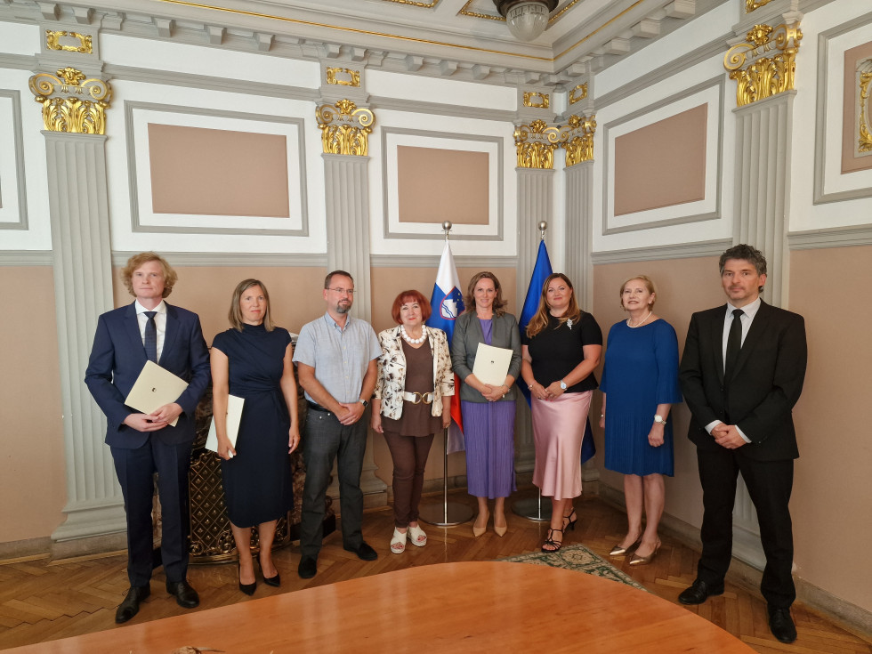 Skupinska fotografija novoimenovanih državnih tožilcev in udeležencev slovesne zaprisege na Ministrstvu za pravosodje. V ozadju sta slovenska in evropska zastava.
