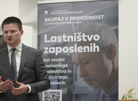 Tilen Božič stoji pred panojem "Lastništvo zaposlenih"