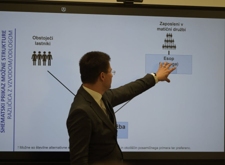 Tilen Božič z levo roko kaže na veliki ekran
