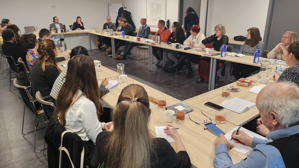 Udeleženci srečanja sedijo za mizo