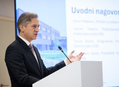 Premier stoji za govorniškim pultom, pred njim mikrofon