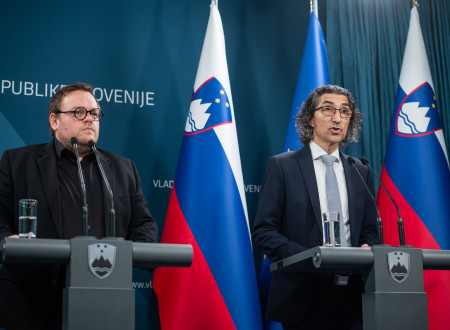 Simon Maljevac in Matjaž Florjanc Lukan stojita za govorniškim pultom, zadaj zastave