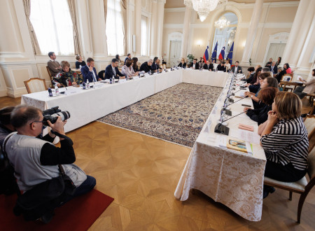 Udeleženci posveta sedijo za mizo v dvorani