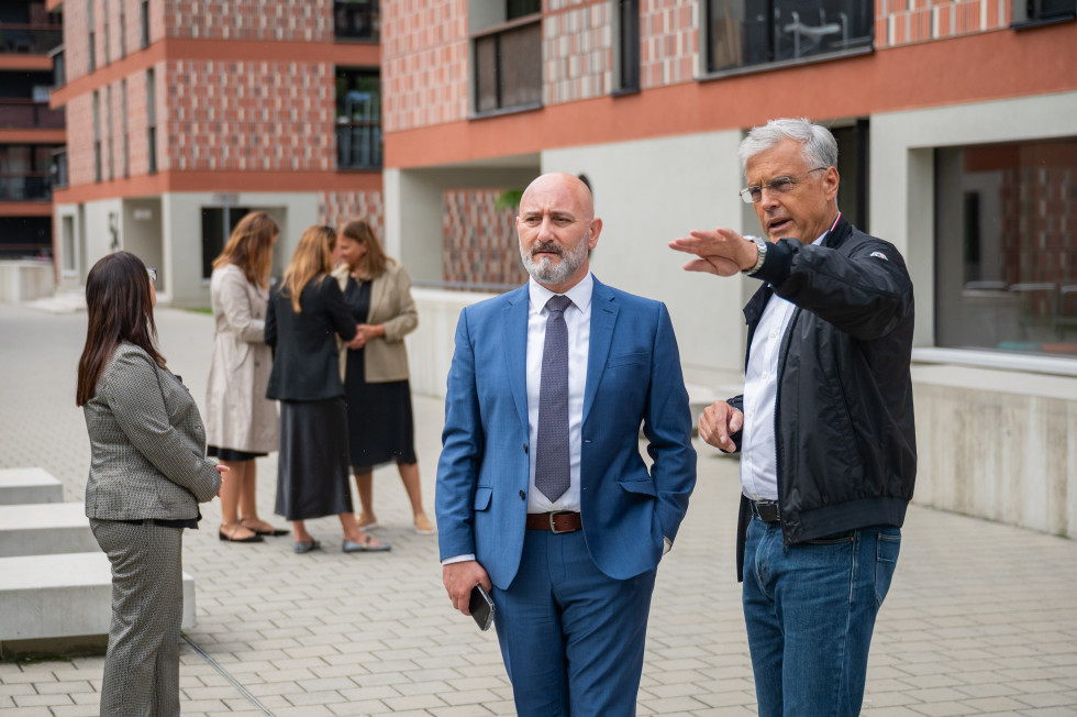 Minister in predsednik uprave stojita pred blokom