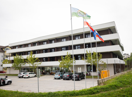 na fotografiji dom za starejše, spredaj zastave