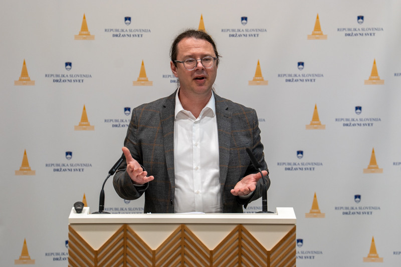 Državni sekretar stoji za govorniškim pultom