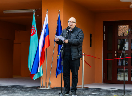 Jan ima nagovor, pred njim mikrofon, zadaj zastave