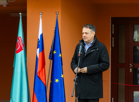 Arčon ima nagovor, pred njim mikrofon, zadaj zastave