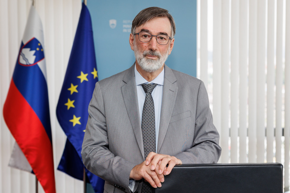Minister dr. Darjo Felda stoji v pisarni, pred pisalno mizo.